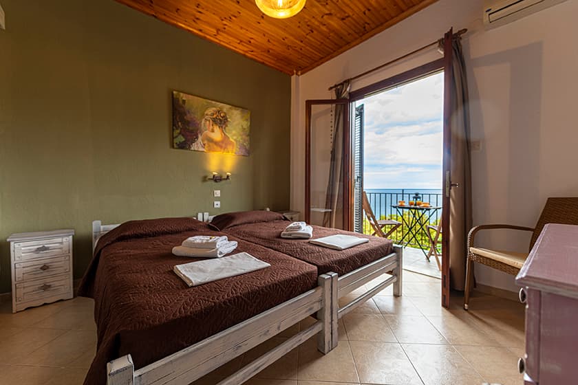 Guest room with a wooden ceiling and a balcony facing the water